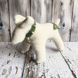 White dog figurine with green holly on a rustic wooden background
