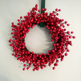 Red berry wreath on a white wall