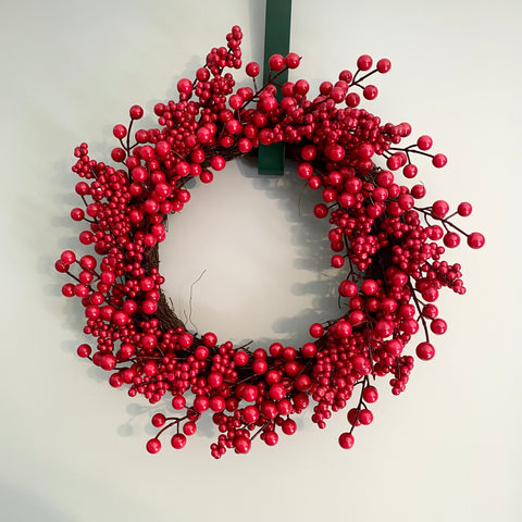 Red berry wreath on a white wall