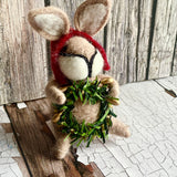Stuffed animal with a wreath and red scarf on a rustic wooden background