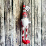 Decorative gnome with striped hat and legs on a wooden background