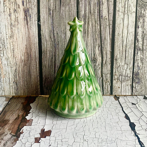 Green ceramic Christmas tree-shaped vase on a wooden surface with a rustic background