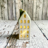 Decorative house-shaped light with gold accents on a rustic wooden surface