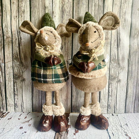 Two plush moose toys wearing plaid and checkered outfits against a wooden background.