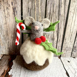Felted mouse figurine on a Christmas pudding with candy cane and berries against a wooden background