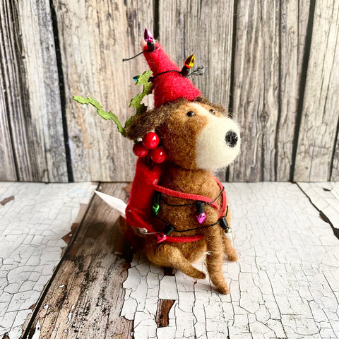 Small stuffed animal wearing a red hat and scarf on a wooden surface