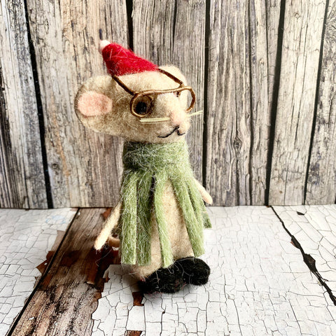 Stuffed mouse toy wearing a red Santa hat and green scarf on a wooden surface.
