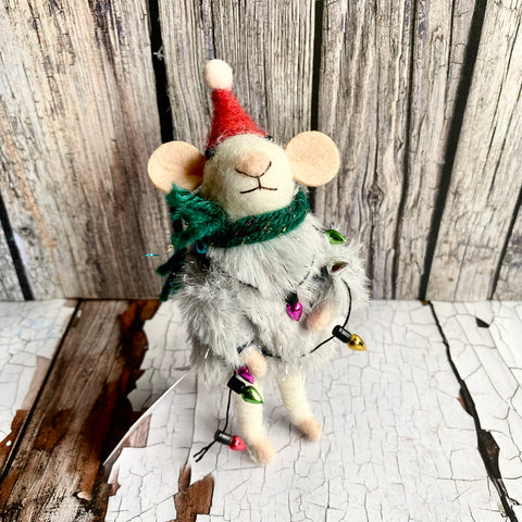 Plush mouse toy with a Santa hat and green scarf on a wooden surface
