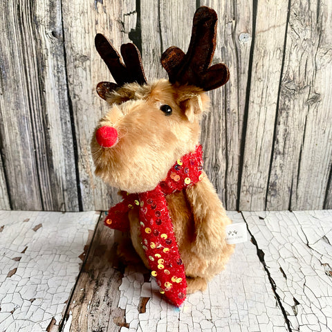 Stuffed reindeer with a red scarf on a wooden surface