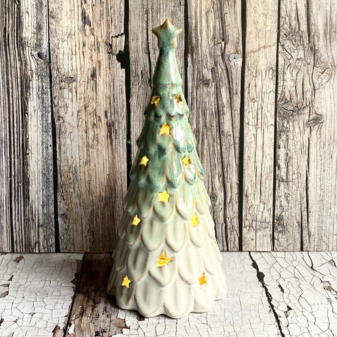 Decorative ceramic Christmas tree with gold stars on a wooden background