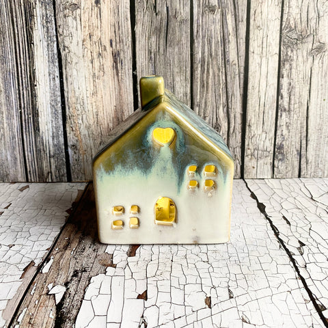 Ceramic house-shaped light with gold accents on a rustic wooden background