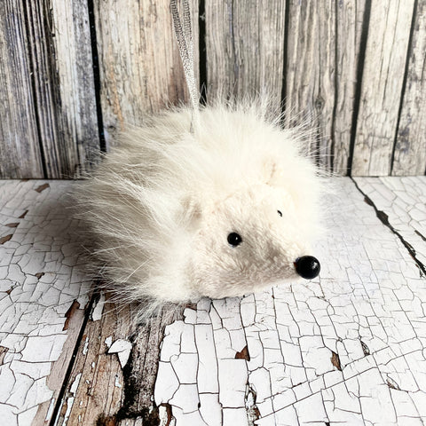 Plush toy hedgehog on a cracked white surface with wooden background