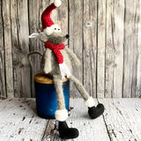 Stuffed mouse wearing a Santa hat and scarf against a wooden background