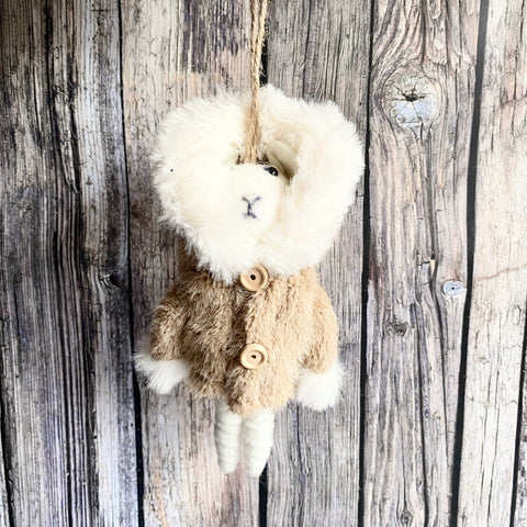 Plush toy mouse in a thick winter coat hanging on a wooden wall